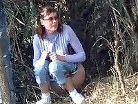 Lady in glasses pees under a tree being unsuspecting of cunning spying